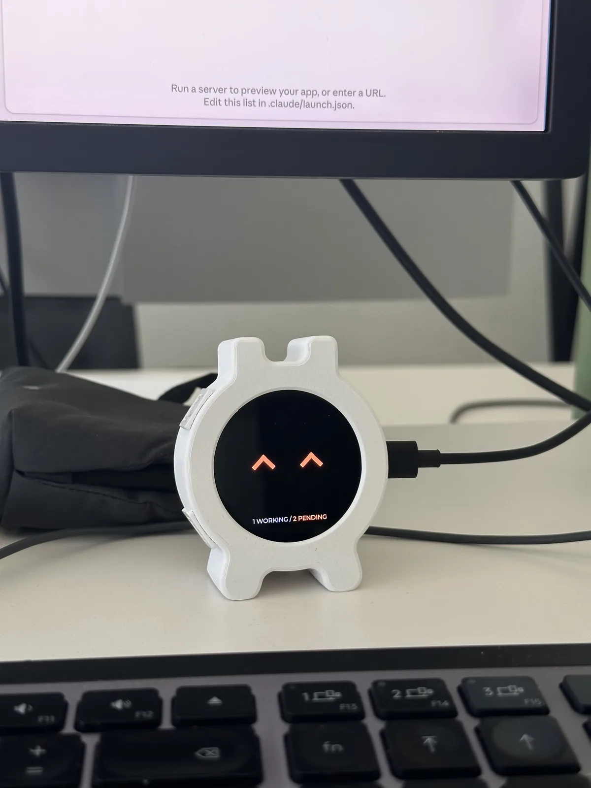 Assembled desk companion showing orange chevron eyes and a count of working and pending sessions